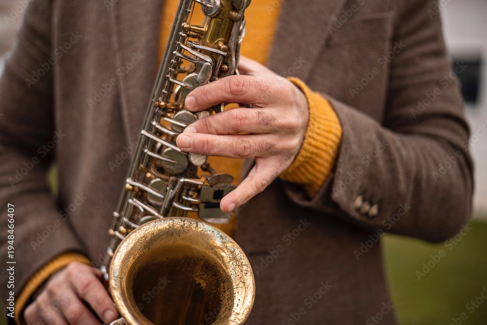 Obraz premium Close-up of hands playing an alto saxophone outdoors