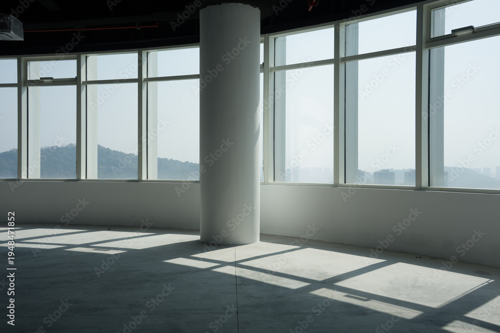 Fototapeta premium Spacious empty office with floor-to-ceiling windows overlooking mountain scenery and natural light