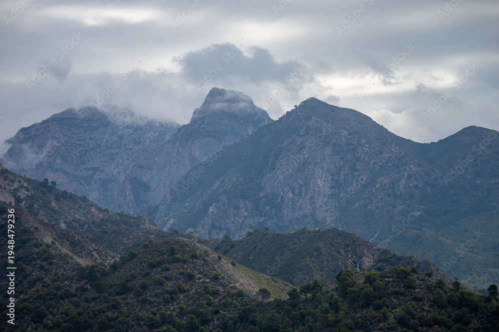 Obraz premium Scenic view of surrounding mountains and picturesque village from a hiking trail along an old irrigation ditch in Frigiliana, Spain.
