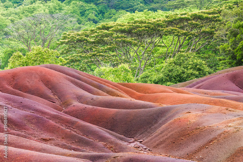 Seven Colored Earth dunes in Chamarel Mauritius with red and purple volcanic sand formations and tropical forest background.