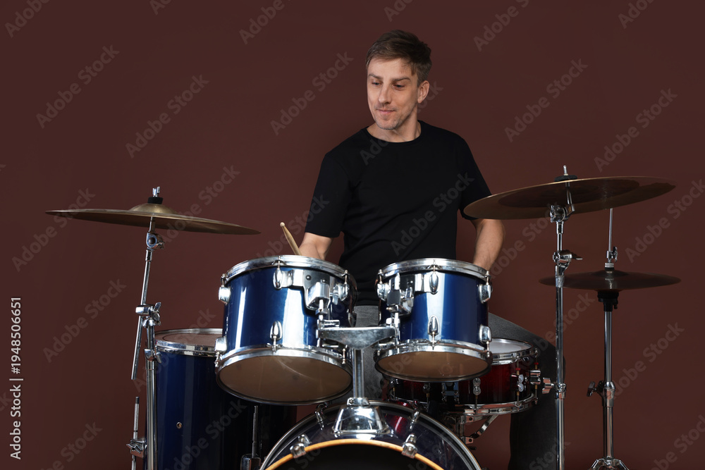 Obraz premium Man playing drums with drumsticks on brown background