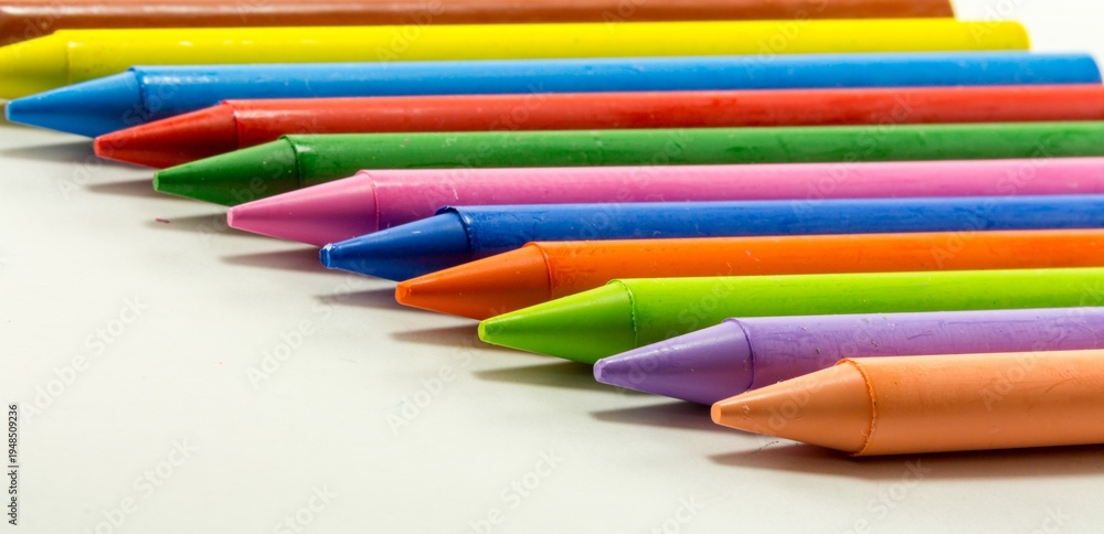Fototapeta premium Colorful Wax Crayons Arranged in a Row on White Background
