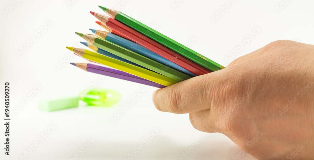 Naklejka premium Hand Holding Colorful Pencils with Sharpener on White