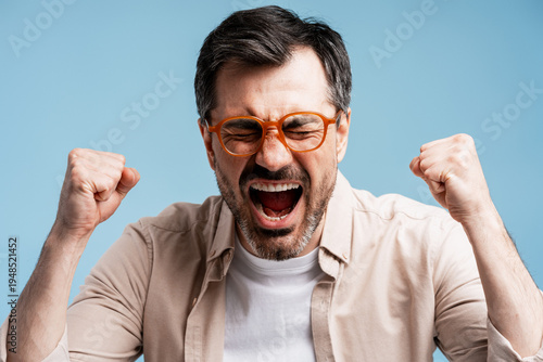 Bilde på lerret Enthusiastic man celebrating victory with closed eyes and triumphant shouting