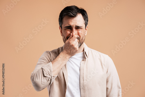 Foto Man pinching nose, reacting to bad smell, feeling disgust and unpleasant odor