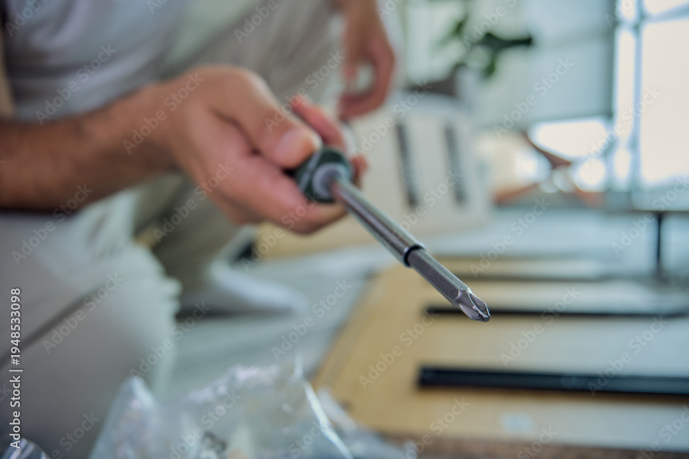 Fototapeta premium Person holding screwdriver assembling furniture at home