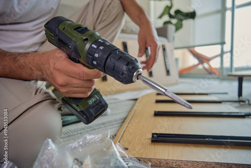 Wallpaper Mural Person's hands holding a power drill assembling flat-pack furniture at home Torontodigital.ca