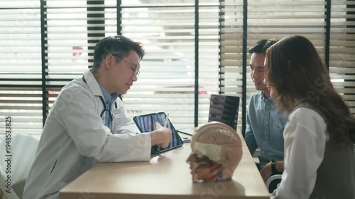 Professional neurologist explaining brain scan results during medical consultation with couple at clinic office focused discussion diagnostic imaging healthcare expertise patient care concept.	