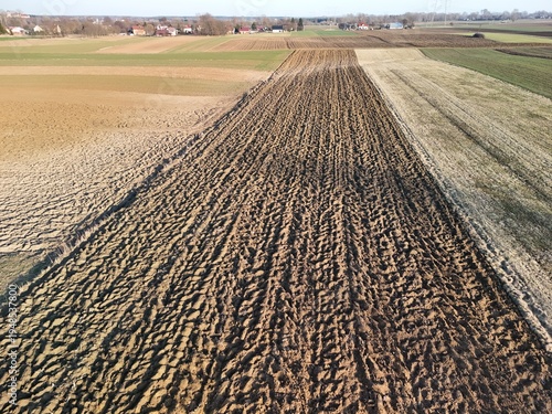Bild auf Leinwand Aerial view of freshly plowed agricultural land showing distinct lines and patterns in the soil, indicating recent farming activity in a rural area under clear skies