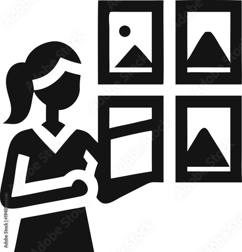 Woman reviewing multiple framed pictures on a wall in a gallery or display setting