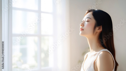 朝の自然光を浴びて深呼吸するリラックスした女性の美容イメージ