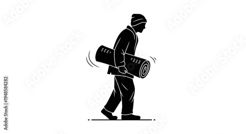 Silhouette of a person carrying a rolled-up carpet or mat, walking outdoors.