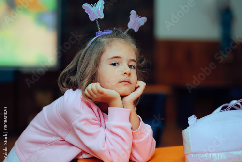 Little Girl with a Butterfly Headband Resting on a School Desk. Happy student thinking and waiting to take a break
