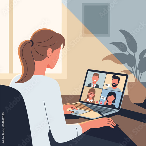 A woman in a video call with coworkers on her laptop in an office