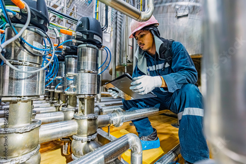 Male work inspection process stainless steel tanks and pipe with a pressure meter in the equipment tank facility for the drink cellar with a vertical