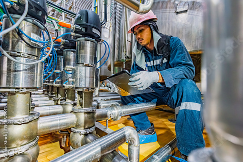 Male work inspection process stainless steel tanks and pipe with a pressure meter in the equipment tank facility for the drink cellar with a vertical