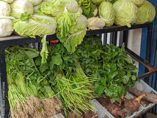 Fresh green vegetables and roots on display at a market stall