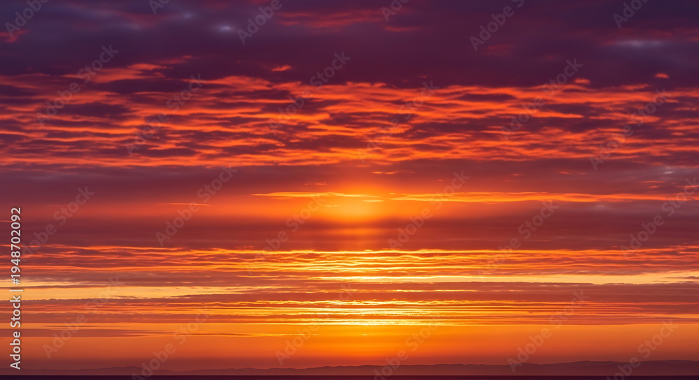 Fototapeta premium Vibrant orange sunset with scattered clouds