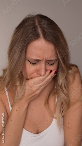 Young blonde woman feeling nauseous, covering her mouth and experiencing discomfort. Health problem, sickness and unwell condition concept