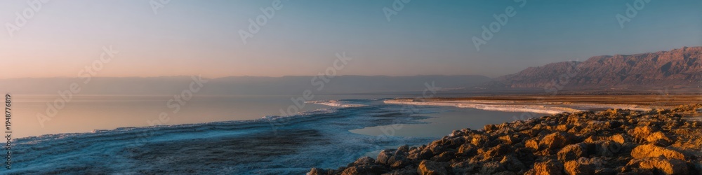 Fototapeta premium Salt lake rugged shoreline with rocky beach at sunset, scenic desert mountains landscape for travel marketing and tourism brochures with copy space