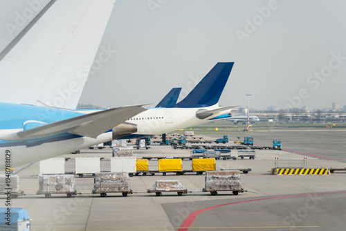 Obraz na plátně Airport apron scene with jet wing, cargo pallets and support vehicles, represent