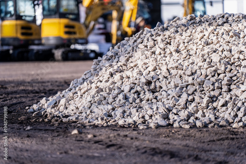 Billede på lærred Heap of light gravel at an active worksite with heavy machinery behind, represen