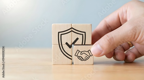 Hand placing protection symbol cube next to handshake symbol cube in bright studio lighting for business security and partnership.