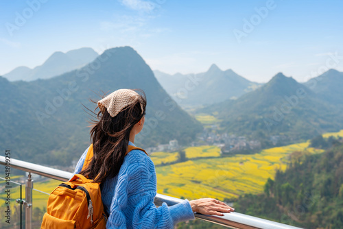 Young happy woman tourist enjoying the canola fields with mountain views while traveling in Luoping, China