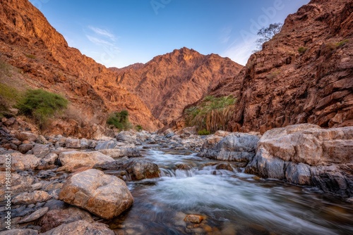 River carves a path through rugged, sunlit canyon walls under a clear, blue sky
