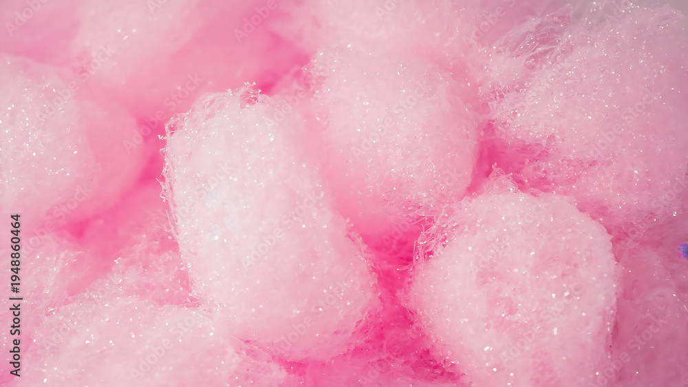 Fototapeta premium Close-up of fluffy pink cotton candy with sparkling sugar crystals, creating a sweet and whimsical texture background.