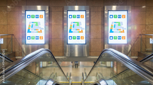 Digital directories displayed on textured ceramic wall near escalators  