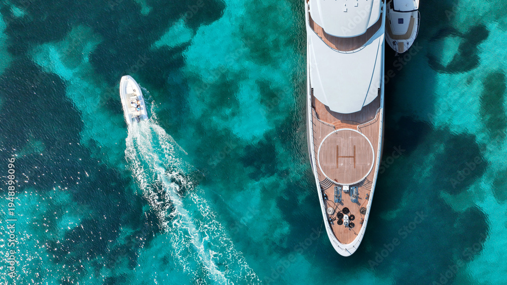 Naklejka premium Aerial drone top down photo of amazing luxury yacht nose with wooden deck and helipad anchored in tropical exotic paradise bay with crystal clear turquoise sea
