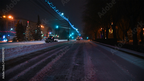Large snow tractor at work on the evening streets of the city