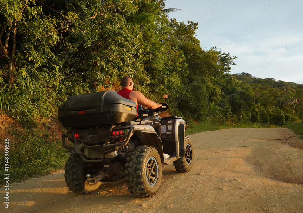 Fototapeta premium A man engages in extreme ATV riding on mountains in the evening