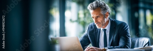 Man in suit focuses intently on laptop screen