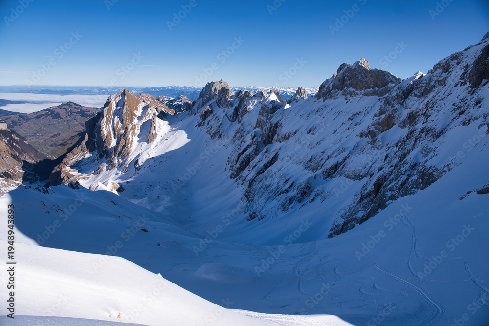 Fototapeta premium Ski descent from the Säntis in the Appenzell Alps. Ski tour in the Alpstein region. From Schwägalp to Toggenburg. Ski tour in rugged terrain. Skier enjoys the view of the snow-covered mountains