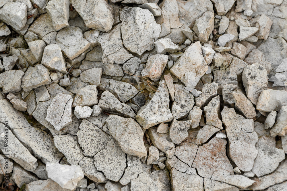 Fototapeta premium Gray broken pebbles close-up, frame filled, cracked dry earth