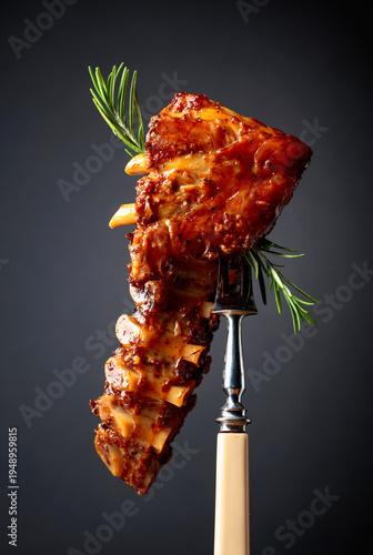 Grilled pork ribs with rosemary on a fork.