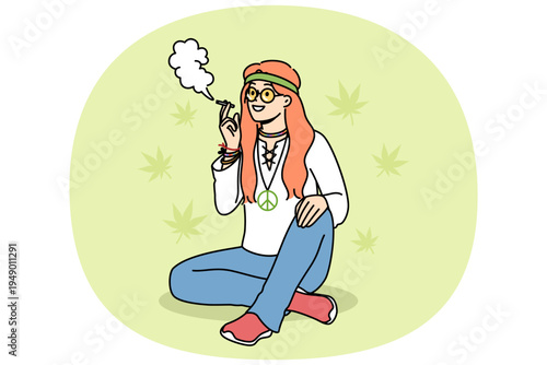 Hippie woman smokes cannabis sitting on summer lawn, enjoying participating in rastafarian community. Young hippie girl in casual clothes uses hashish and cannabis to relax and improve mood.