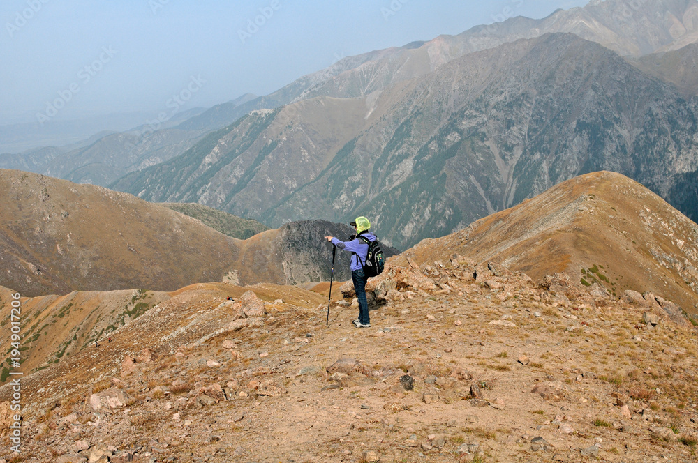 Obraz premium Epic mountain vista with a trekking trail on a steep ridge overlooking a deep valley in Tian Shan