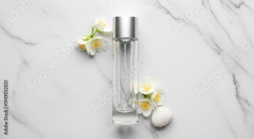 Clear perfume bottle with silver cap on marble background with white flowers
