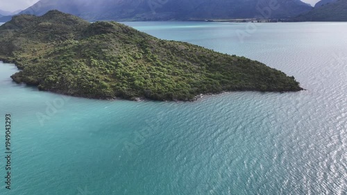 flying around Pigeon Island, located  in the middle of Lake Wakatipu, near Glenorchy in South Island region of Otago, New Zealand, surrounded by mountain landscape - 4k aerial video footage