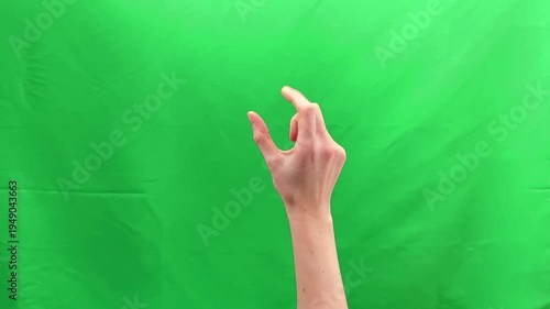 Two fingers performing pinch zoom gesture on green chroma background. Human hand enlarging digital image through touch screen interaction. Mobile interface navigation concept for scale control.
