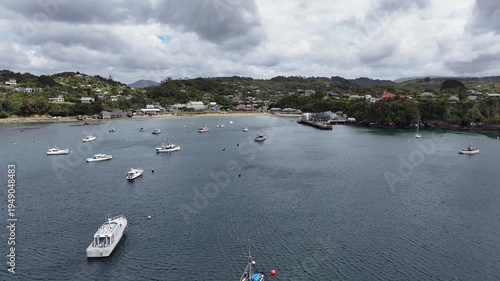 Aerial landscape view, flying across Halfmoon Bay toward Oban, a settlement on Stewart Island, New Zealand, with Ferry Terminal, beach and hilly wooded landscape in background 4k aerial video footage 
