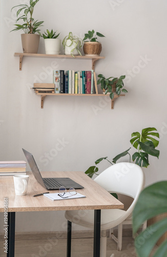 Modern home office creating calm and focused environment for remote work, creative tasks. Home office workspace with laptop plants