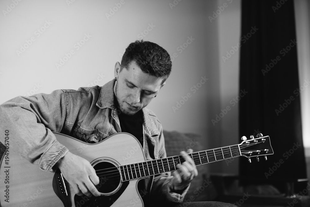 Obraz premium Young musician composing music playing acoustic guitar at home