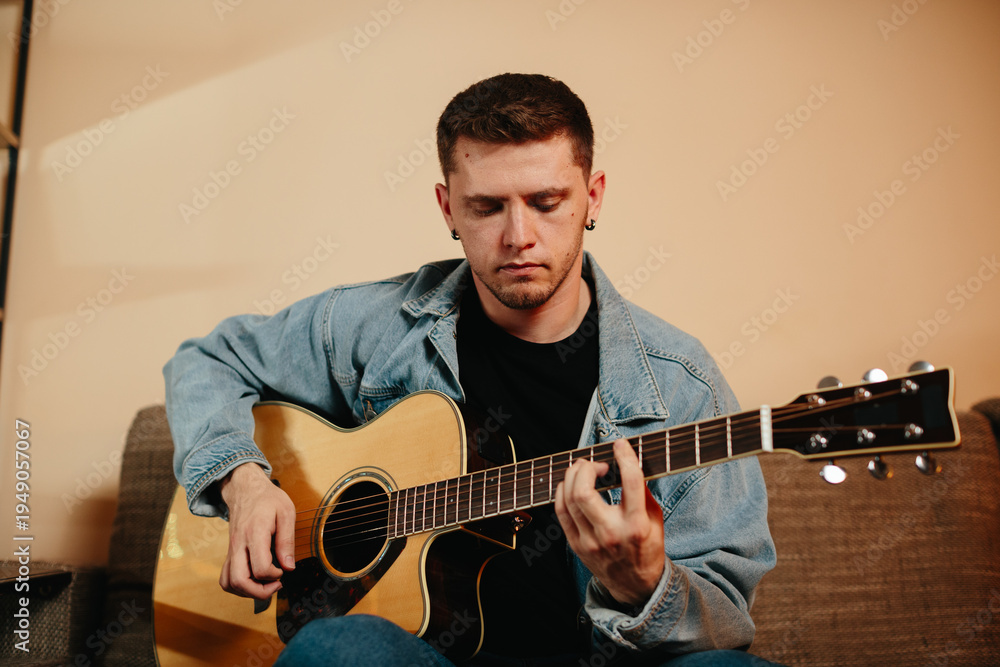 Obraz premium Young musician composing music playing acoustic guitar at home
