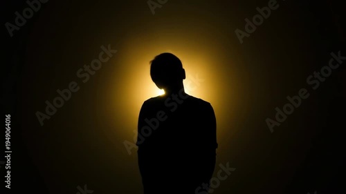 Silhouette of a person against a bright golden light background
