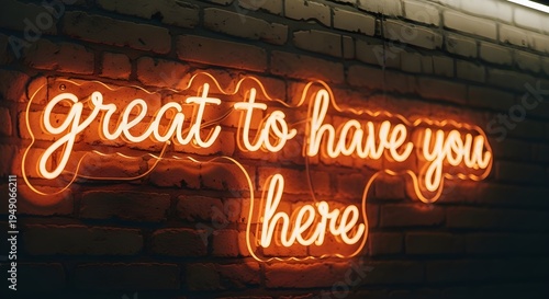 Warm orange neon sign displaying the welcoming cursive message great to have you here against a dark brick wall