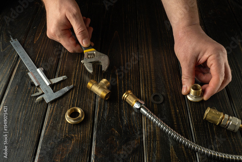 Professional plumber working at workbench in workshop. Process of repairing gas equipment or connecting brass fittings